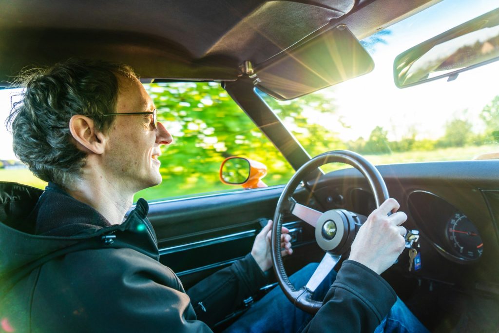 man in green jacket driving car during daytime